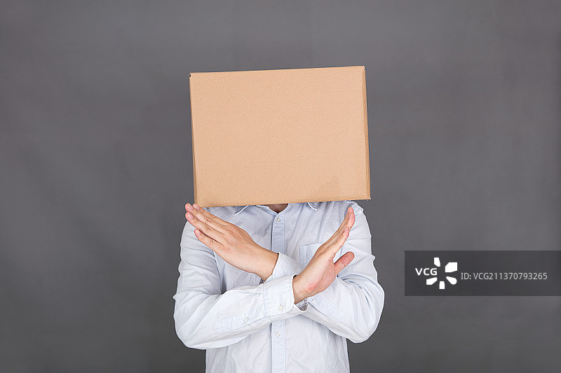 头戴纸箱的男士双手合十做拒绝手势图片素材