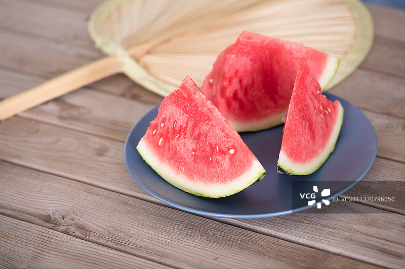 一盘三块西瓜和一把蒲扇图片素材