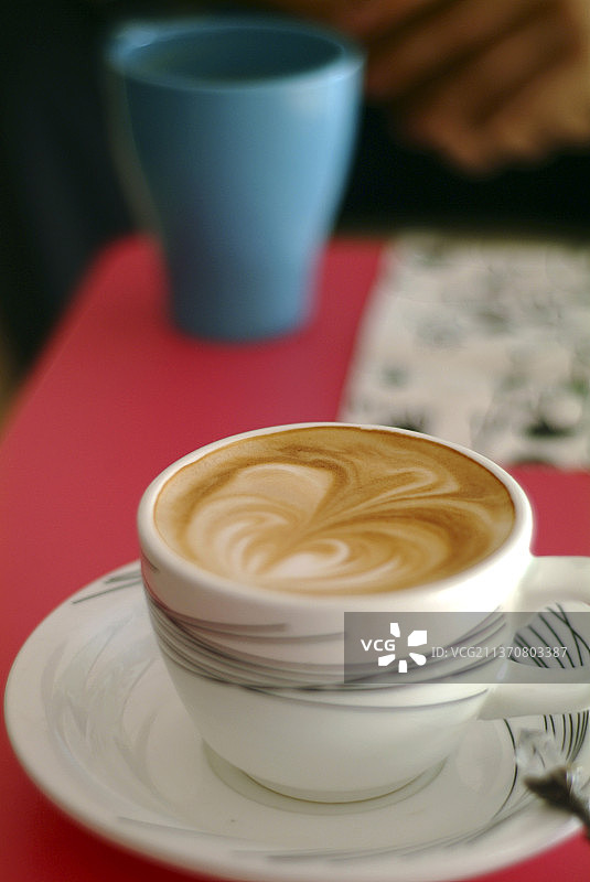 红色桌子上放了一杯卡布奇诺咖啡图片素材
