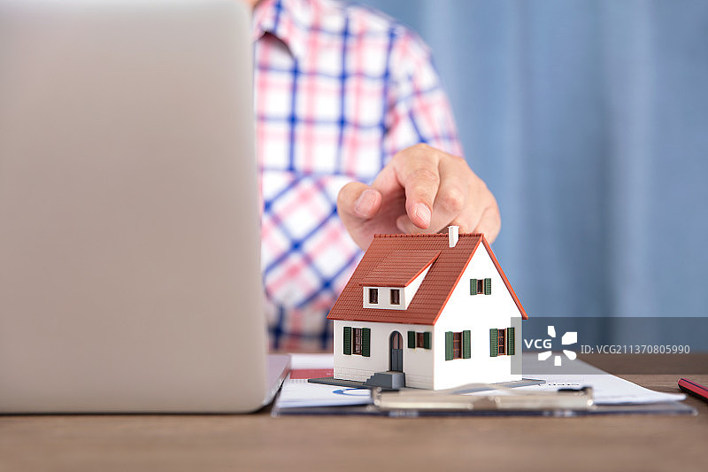 商品房销售人员手指电脑旁的房子模型图片素材