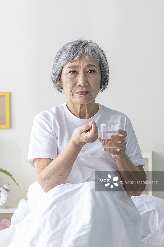 独居老人坐在床上吃药图片素材