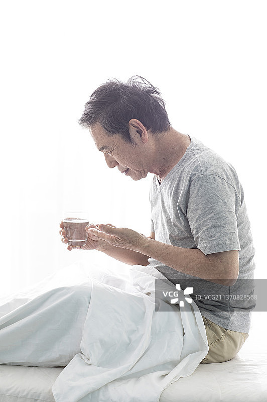 独居老人坐在床上吃药图片素材