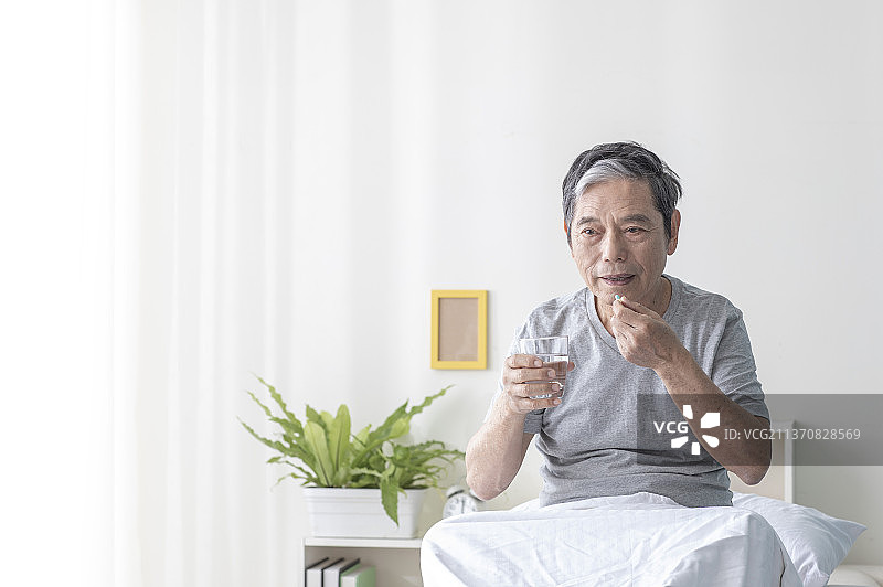 独居老人坐在床上吃药图片素材