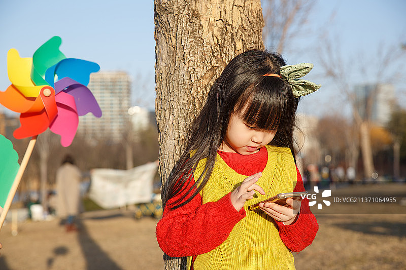 在户外看手机的小女孩图片素材