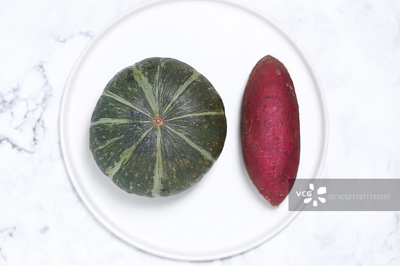 放在白色盘子里的一个南瓜和番薯图片素材