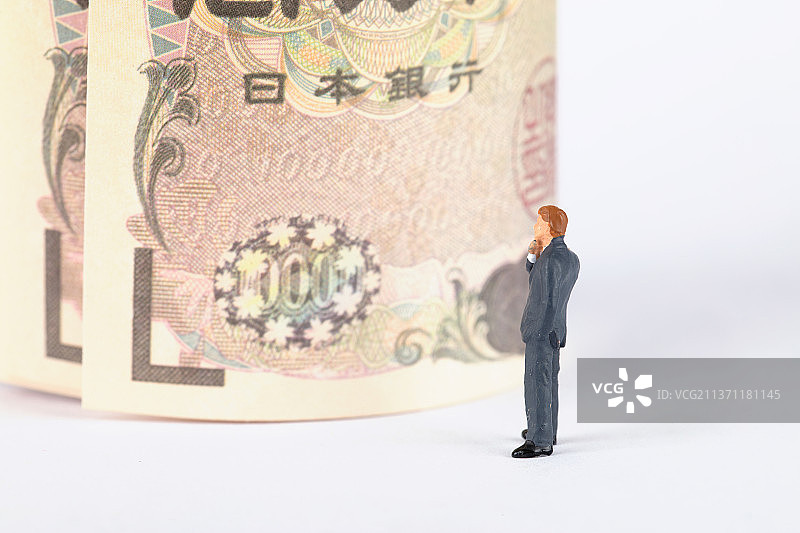 商务微缩男士看着一卷日元纸币发呆图片素材