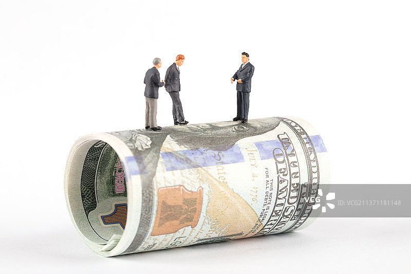 一卷美元钞票上三名商务男士人偶模型在商议图片素材