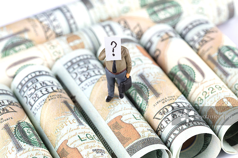 微距模型概念打电话的商务男士模型一脸问号的站在美金钞票上图片素材