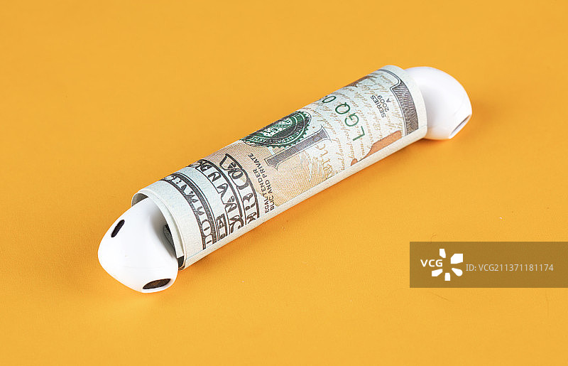 卷着的美元钞票两头各放一个蓝牙耳机图片素材