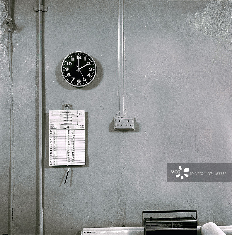 1982年日历，废弃工厂办公室里的时钟和收音机（伦敦东区）图片素材