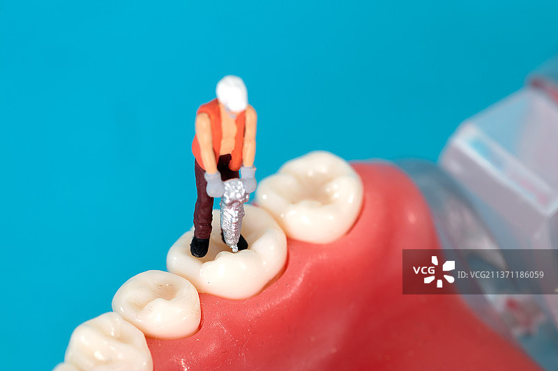 手拿钻头的工人人偶在牙齿上钻洞图片素材