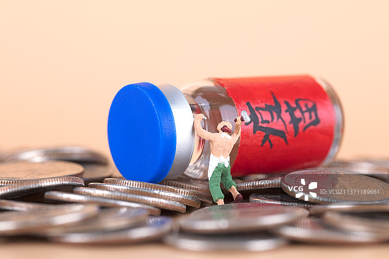 试图凿开硬币上疫苗药物的微缩人偶图片素材