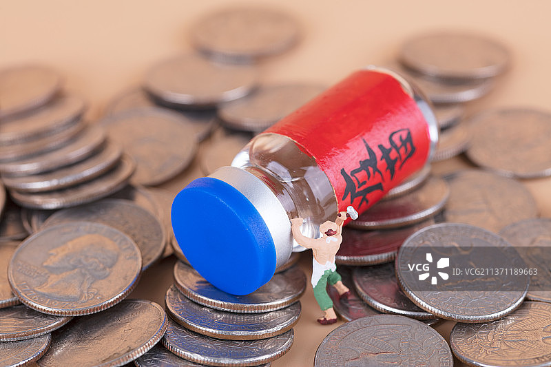 试图凿开硬币上疫苗药物的微缩人偶图片素材