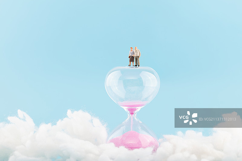 白云中沙漏上的老人人偶图片素材
