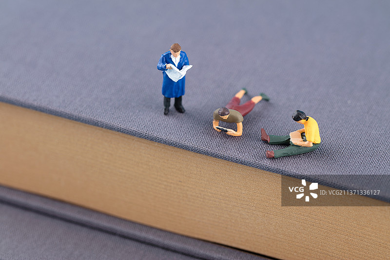 书上微缩的人偶在安逸的看书图片素材