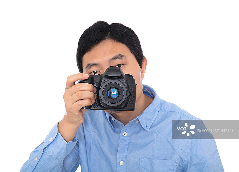 男摄影师拿着相机拍照在白背景前图片素材