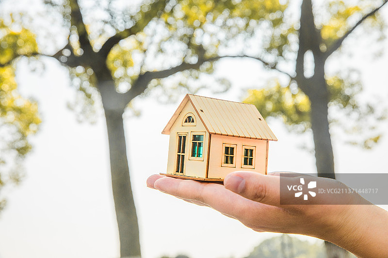 房子模型，一个房子模型放在草地上，一个房子模型用手举起图片素材