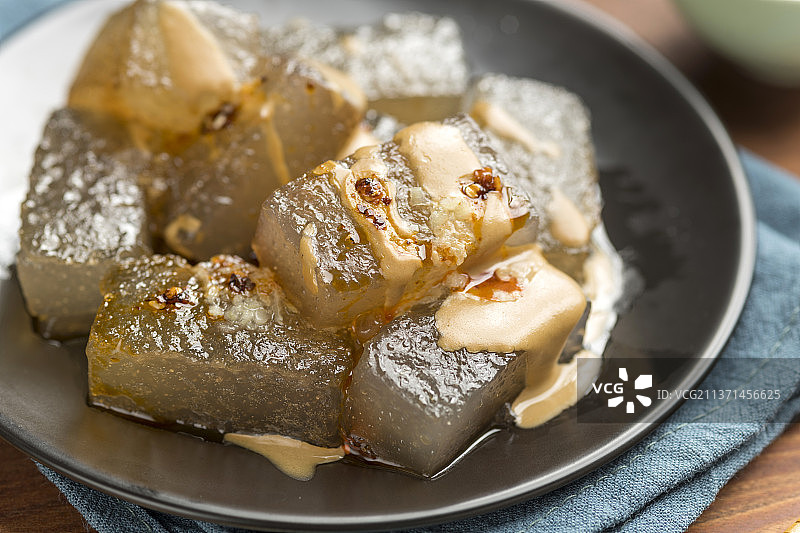 天津小吃焖子特写木桌面深色调图片素材