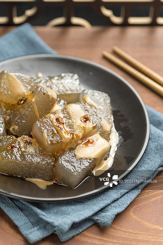 天津小吃焖子特写木桌面深色调图片素材