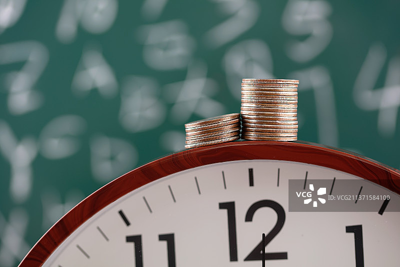 美元硬币在黑板前的钟表上图片素材