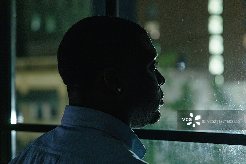 特写：男人在夜晚望向窗外图片素材