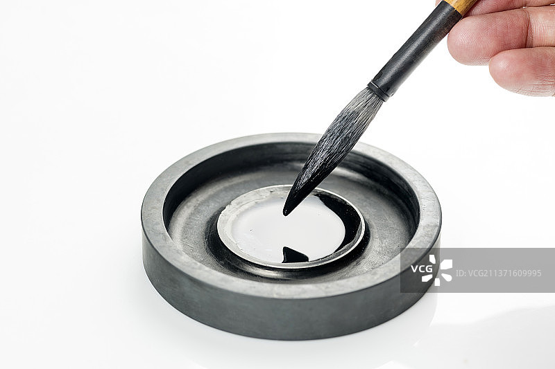 手持毛笔蘸墨特写白色背景图片素材