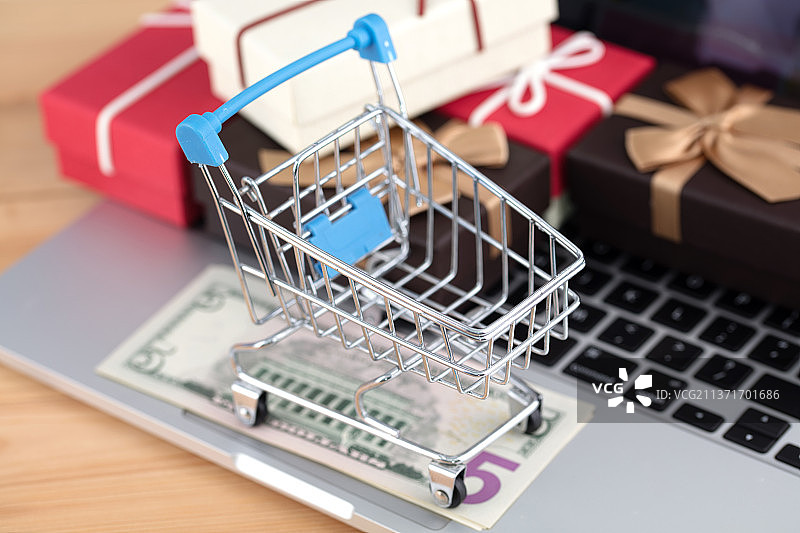 购物车压着钞票在电脑上及礼品图片素材