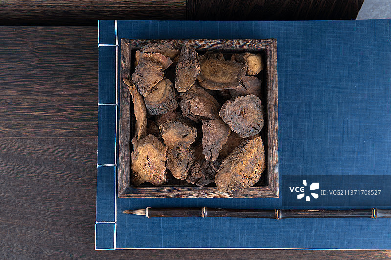 中药大黄在木盒里在药书上图片素材