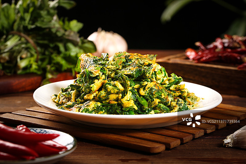 木垫上放着一盘荠菜炒鸡蛋图片素材