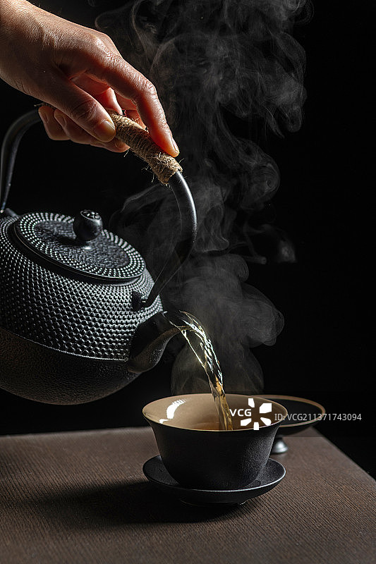 手持茶壶向盖碗中倒茶特写深色调图片素材
