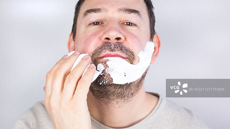 灰色背景上刮胡子的男人肖像图片素材