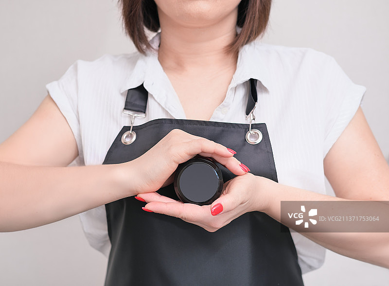 女美容师身穿围裙，手拿化妆品容器图片素材