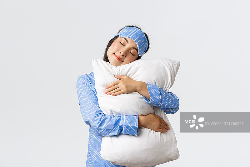 戴着眼罩拥抱舒适物品的可爱亚洲女孩图片素材