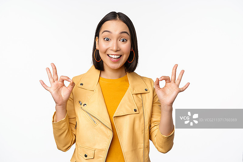 面带微笑的漂亮韩国女孩，看起来很满意，比着OK手势图片素材