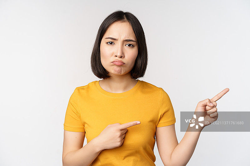 失望的亚洲女孩指向右边的特写图片素材