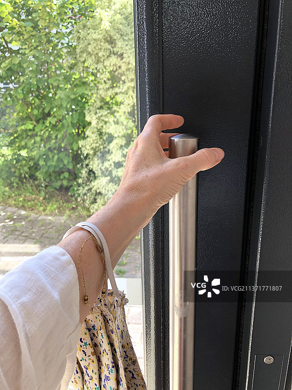 出门，女人打开门的裁剪手部图片素材