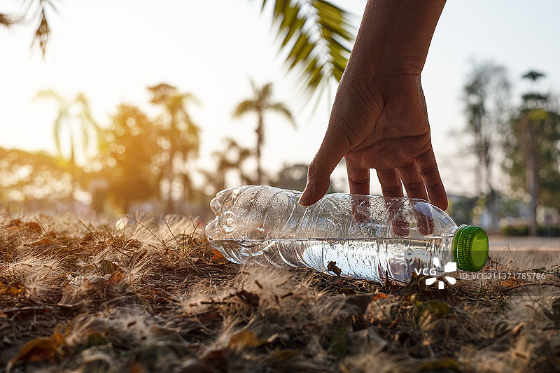 特写镜头：手捡起透明塑料水瓶图片素材