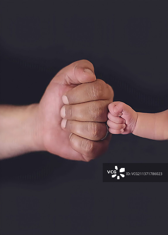 黑色背景下父亲牵手图片素材