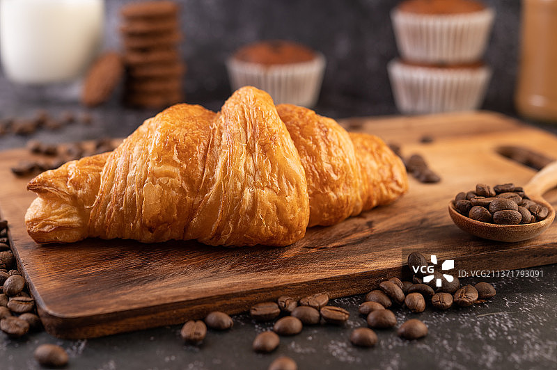 木制平台上的牛角面包和咖啡豆图片素材