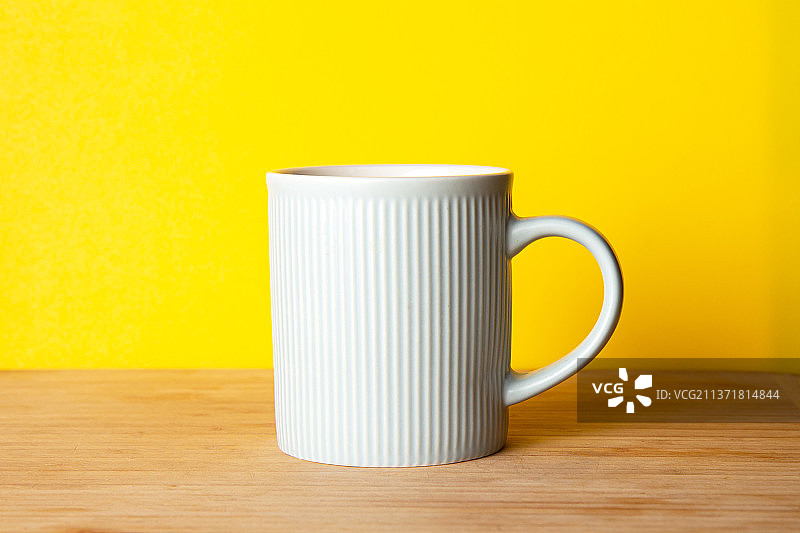 明亮黄色背景上的蓝色陶瓷杯图片素材