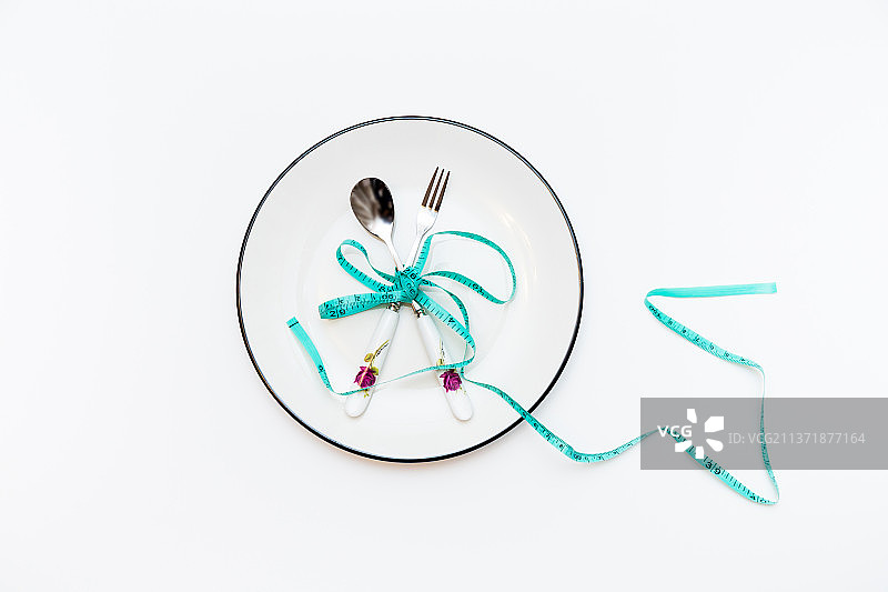 盘子里被皮尺捆扎的餐具，健康，减肥，瘦身主题概念图片素材