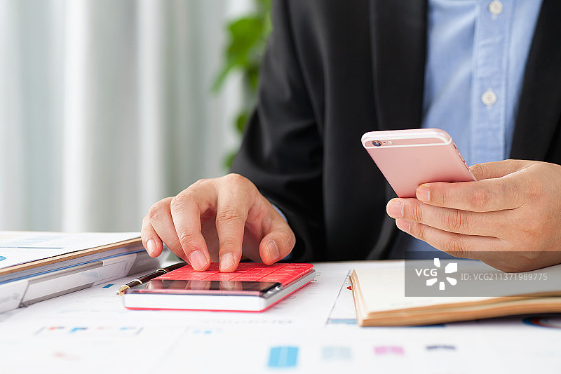 边使用计算器边使用手机的工作者图片素材