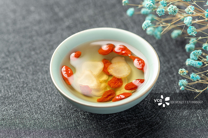 西洋参枸杞茶摆放在黑色背景上图片素材