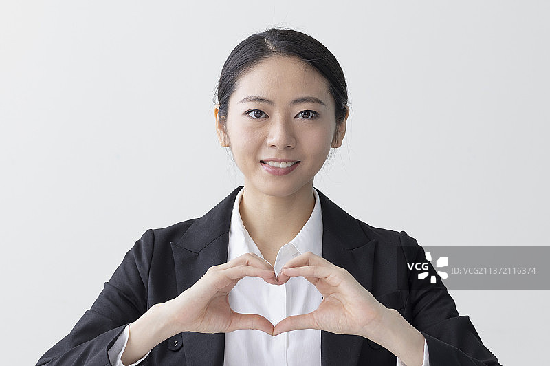 东方美女微笑地作爱心的手势图片素材