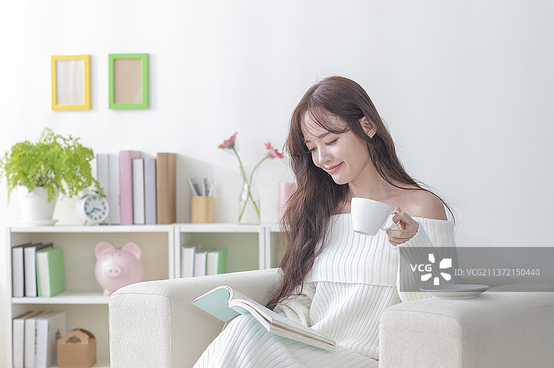 东方美女坐在沙发上看书图片素材