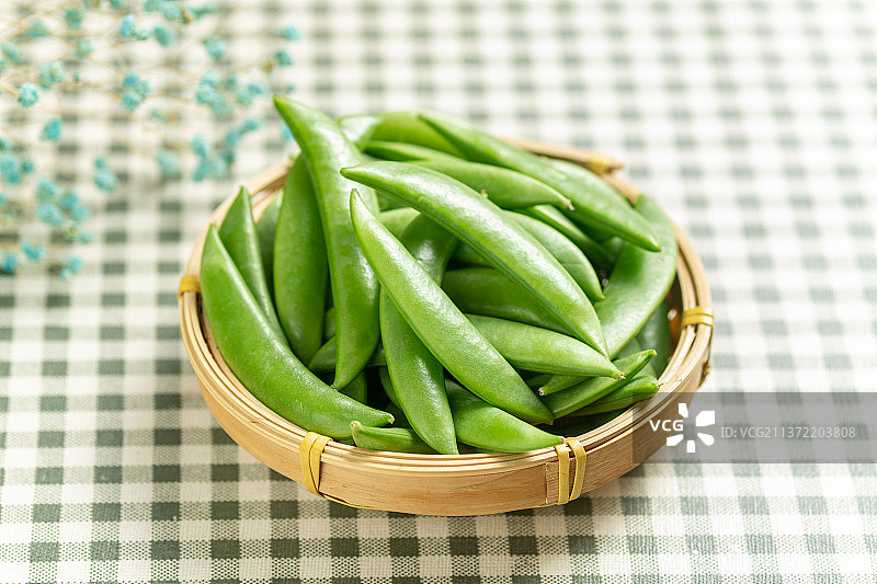 一簸箕甜豆摆放在格子桌布上图片素材