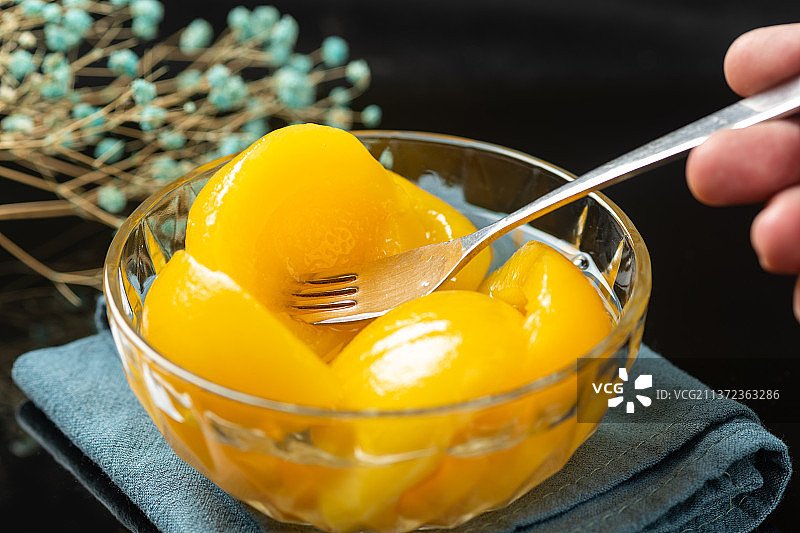 一碗黄桃罐头特写黑色背景图片素材