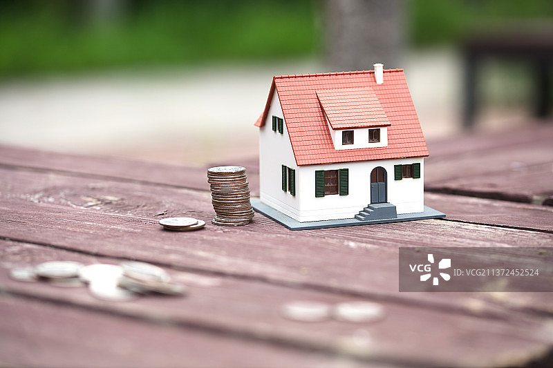 房屋模型和硬币在公园椅子上图片素材