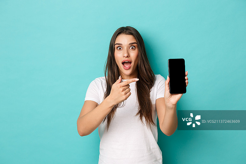 身穿白色T恤的惊讶女子人像，用手指指向前方图片素材