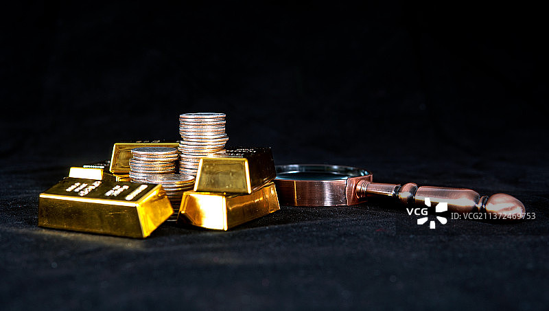 黑背景上的金条和放大镜及硬币图片素材